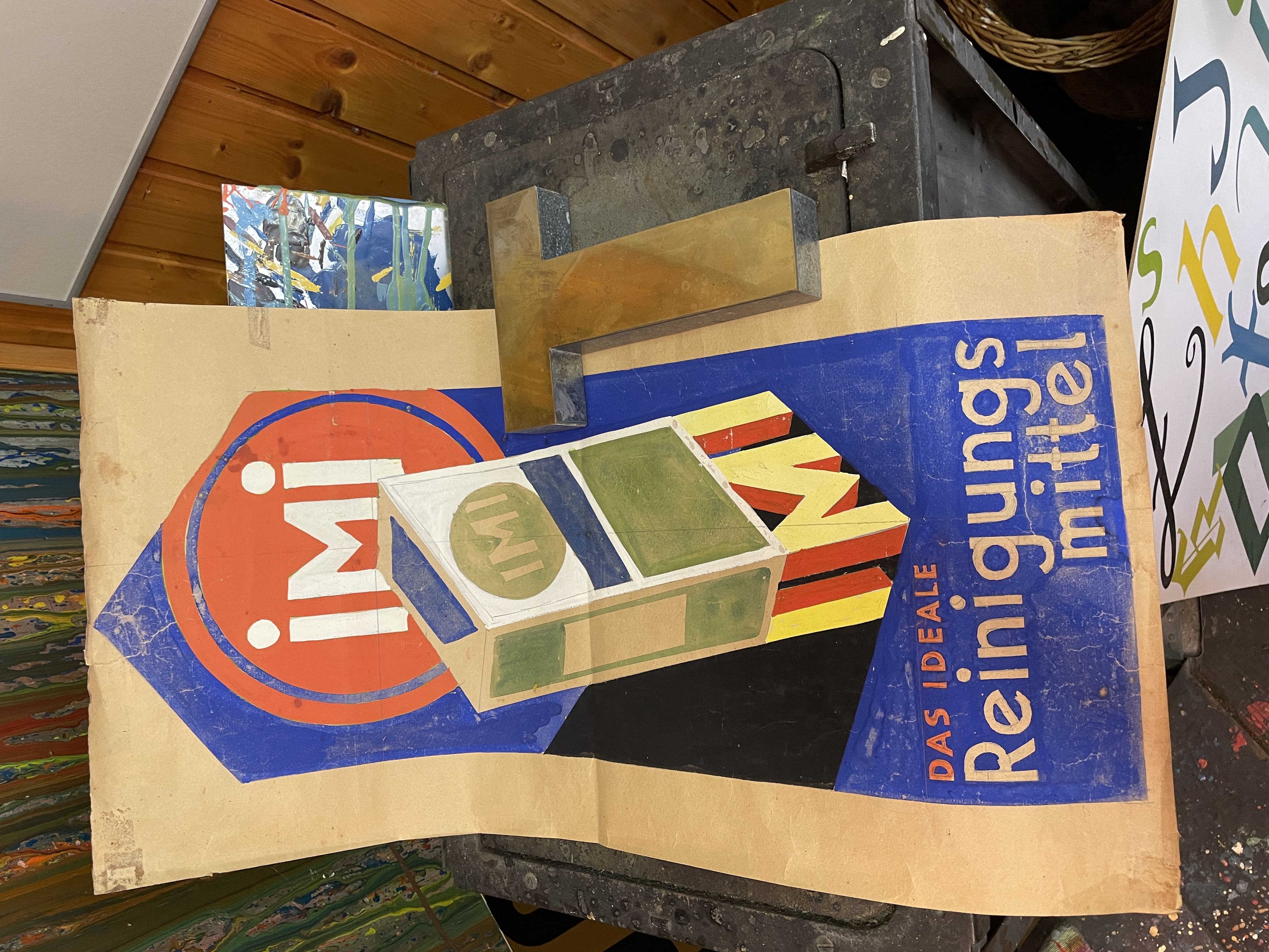 Entwurf auf Papier für ein Schild für das Reinigungsmittel iMi, oben in einem Kreis der Schriftzug iMi, darunter eine Verpackung mit der Aufschrift IMI (!), die auf einem Sockel steht, der aus den 3D-Buchstaben IMI (!) gebildet wird, darunter der Text: „DAS IDEALE Reinigungsmittel“