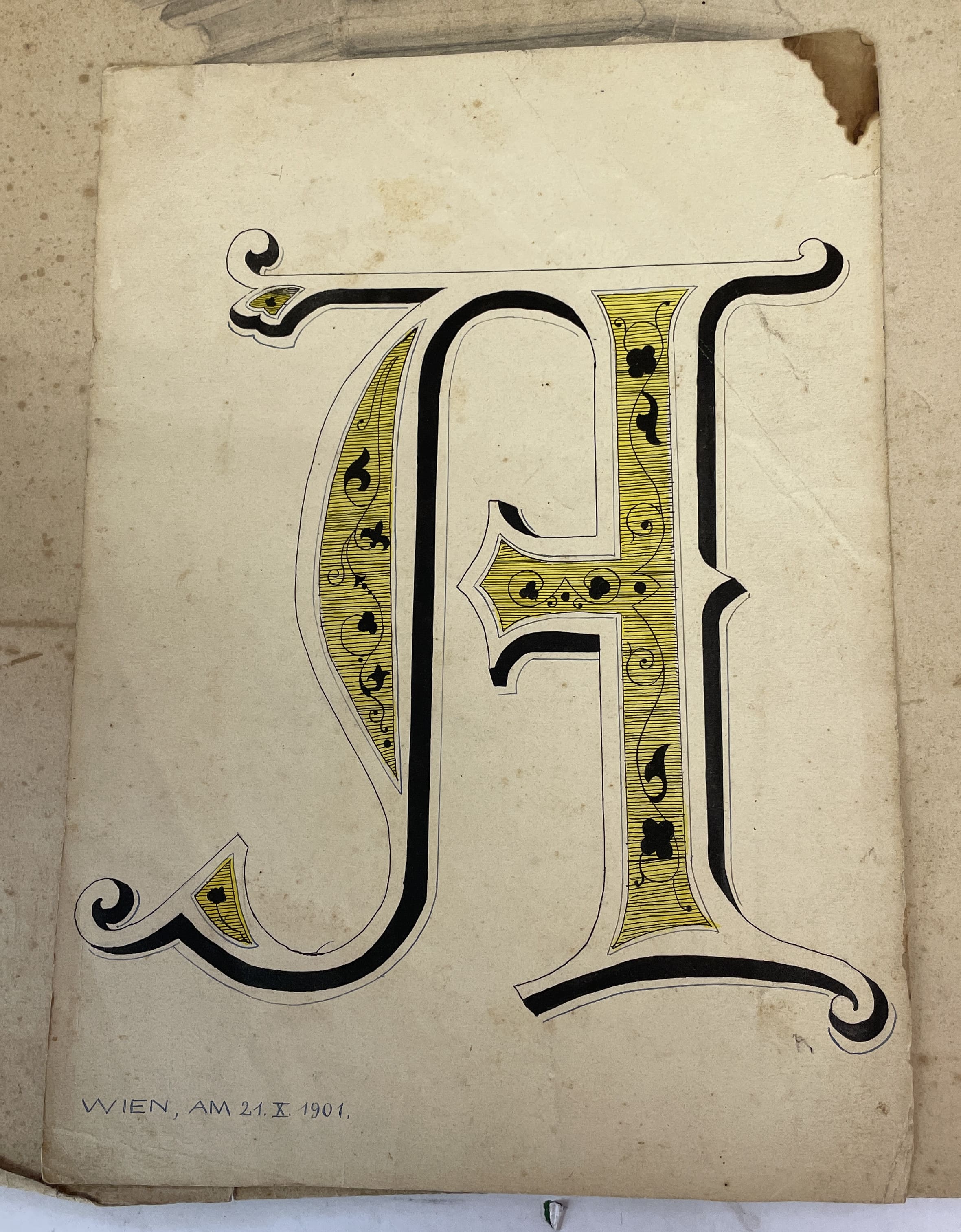 3D-Tuschezeichnung des Buchstabens A in einer sehr altmodischen Schrift, die Innenteile sind gelb ausgemalt und mit feinsten Linien und Verzierungen dekoriert, links unten der Text „WIEN, AM 21. X. 1901.“