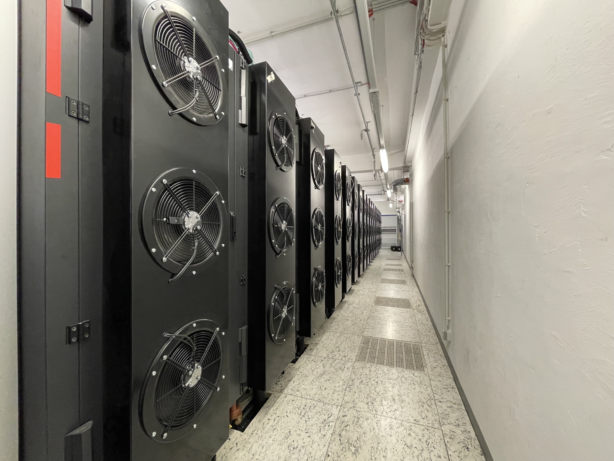 Blick in den Gang an der Hinterseite der Racks, die Rückseiten der Racks enthalten jeweils drei große Lüfter