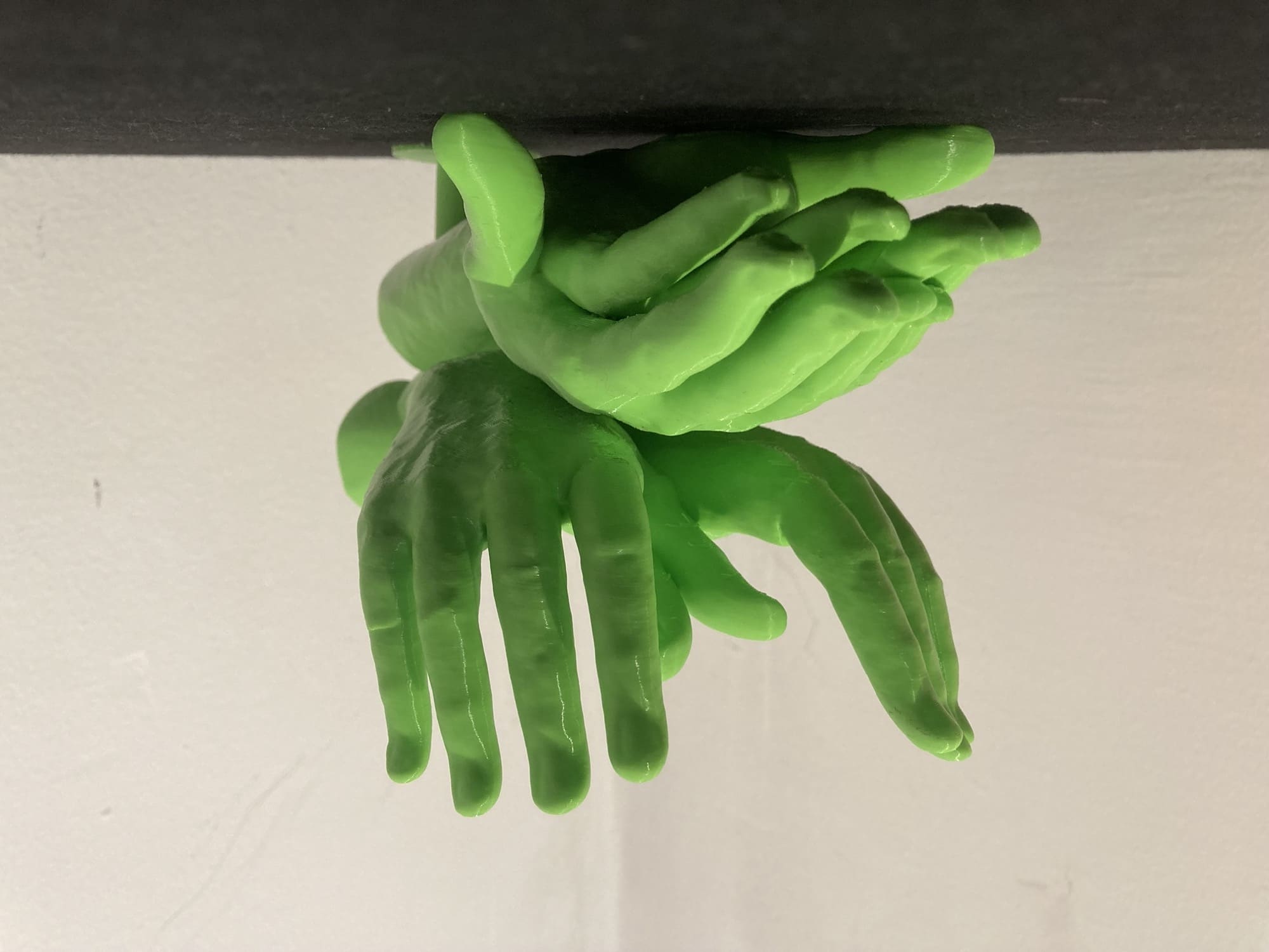 eine 3D-gedruckte Skulptur aus grünem Filament, es sind vier Hände, die die Gebärden für Schildkröte und Schmetterling zeigen